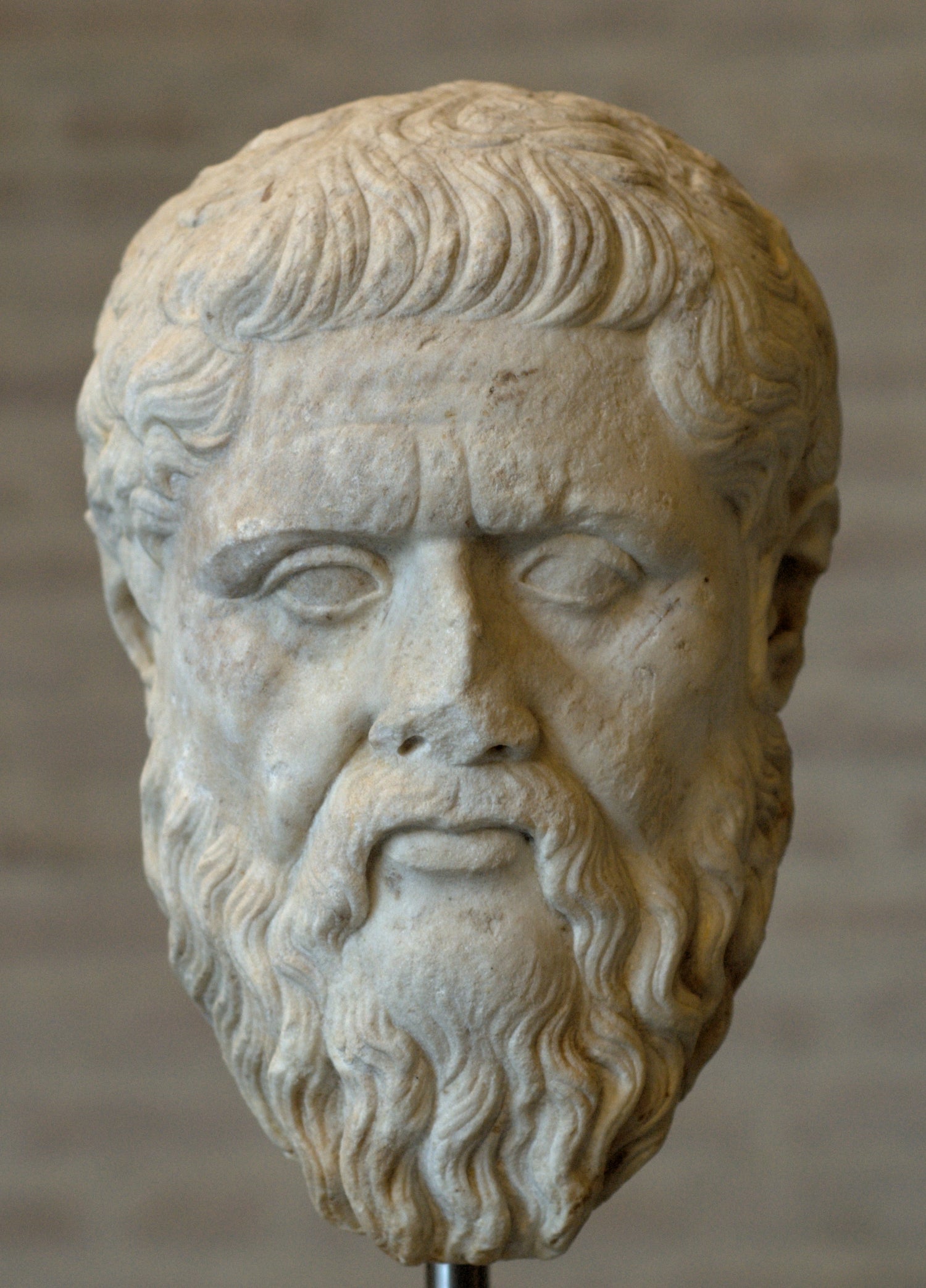 Stone sculpture of a bearded man's head against a plain background. Plato